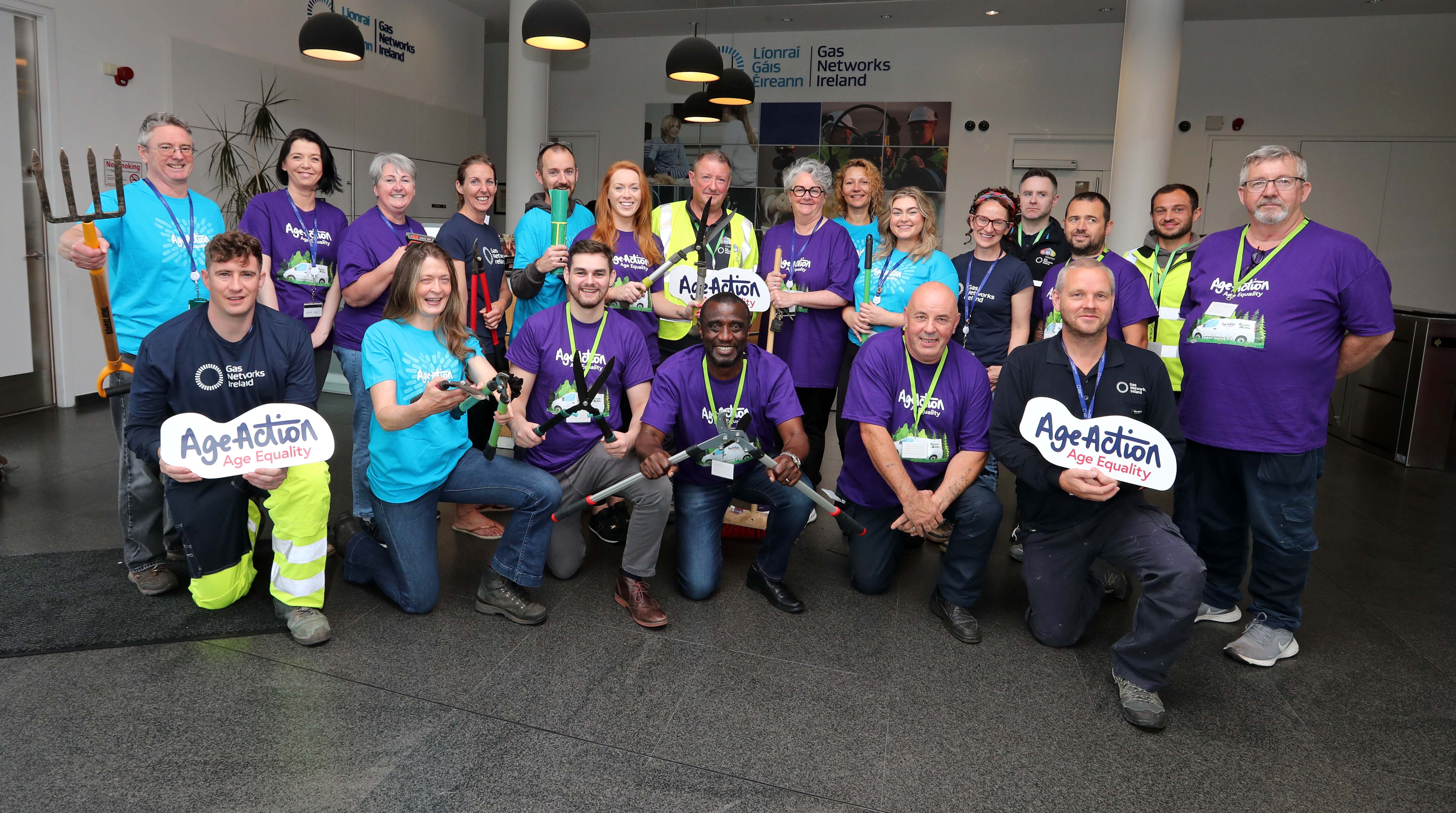 Corporate company volunteers kneeling and holding age action signs 